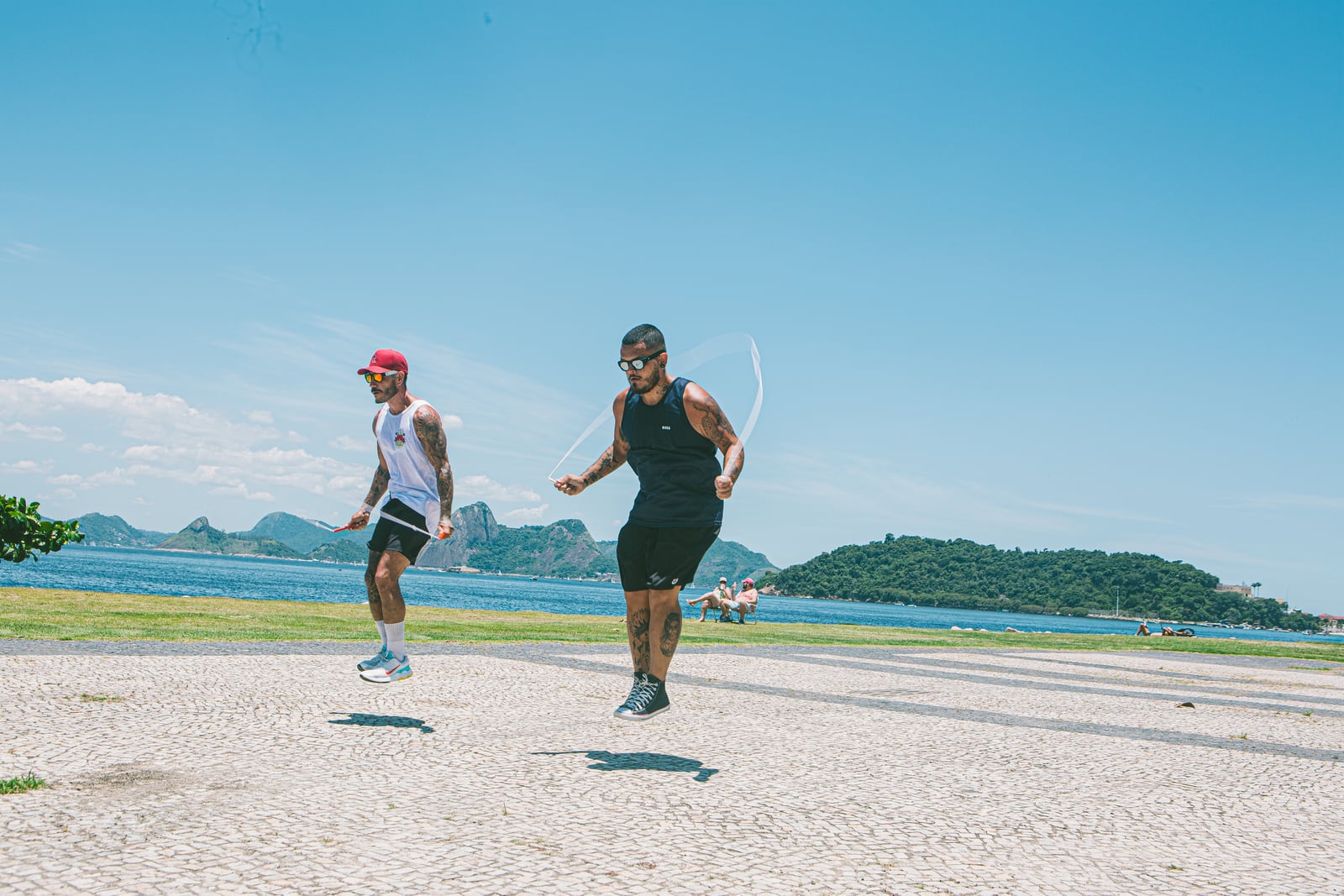 Dois praticantes pulando corda no calçadão do Aterro do Flamengo, de frente para a baía